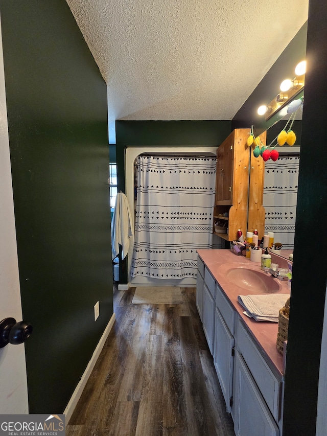 bathroom with hardwood / wood-style floors, vanity, curtained shower, and a textured ceiling