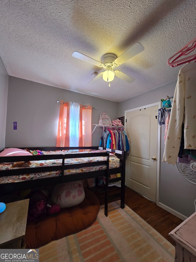 bedroom featuring ceiling fan, wood-type flooring, and a textured ceiling