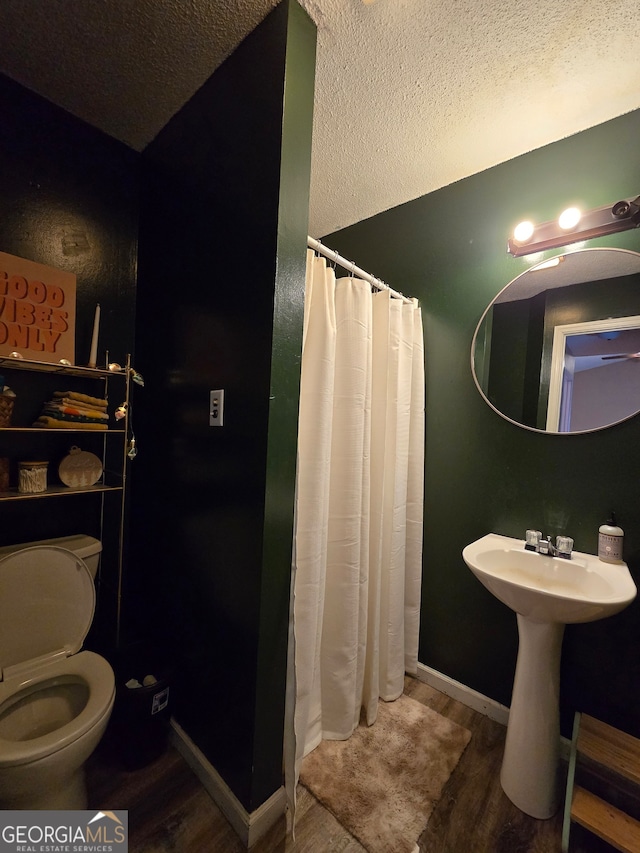 bathroom with walk in shower, toilet, a textured ceiling, and hardwood / wood-style flooring