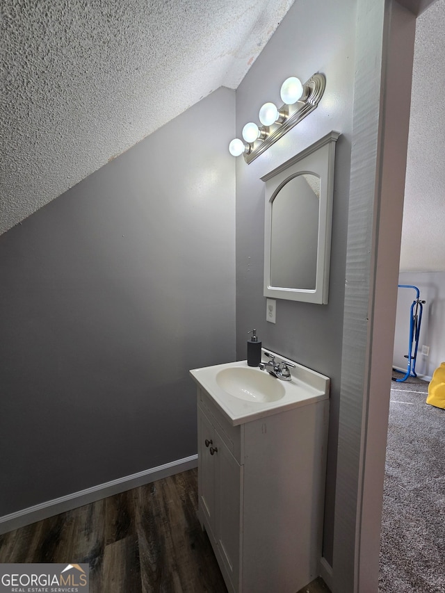 bathroom featuring a textured ceiling, hardwood / wood-style floors, vanity, and lofted ceiling