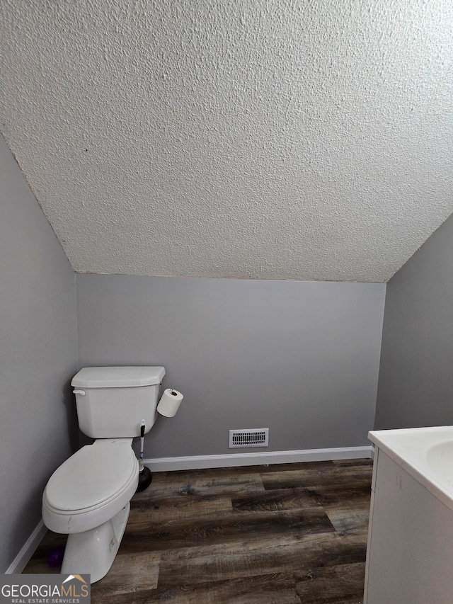 bathroom featuring hardwood / wood-style floors, a textured ceiling, toilet, and lofted ceiling