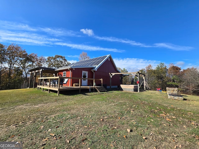 view of home's exterior with a wooden deck, a yard, and solar panels