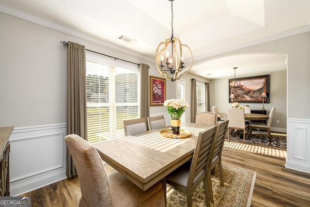 dining space with ornamental molding, an inviting chandelier, dark hardwood / wood-style flooring, and a tray ceiling