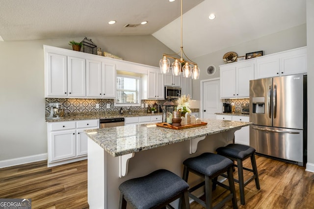 kitchen featuring a kitchen island, white cabinets, pendant lighting, and appliances with stainless steel finishes