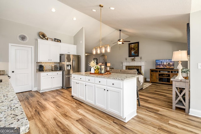 kitchen with stainless steel refrigerator with ice dispenser, tasteful backsplash, white cabinets, and lofted ceiling