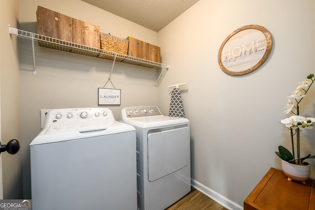 clothes washing area with washer and clothes dryer, dark hardwood / wood-style floors, and a textured ceiling