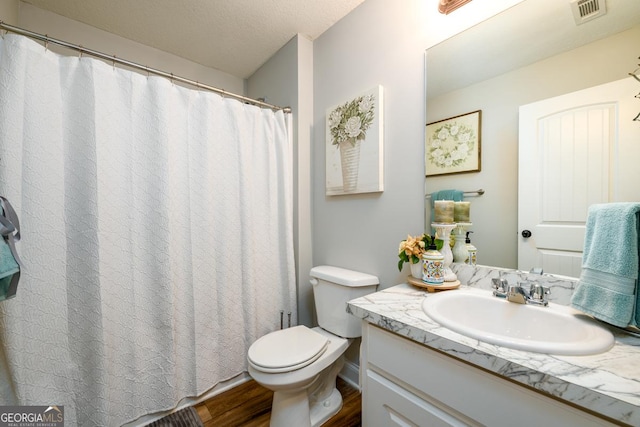 bathroom with hardwood / wood-style flooring, a textured ceiling, toilet, and vanity