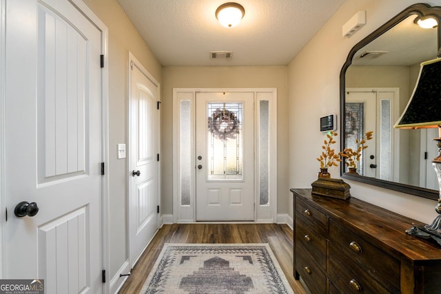 foyer with a textured ceiling and dark hardwood / wood-style flooring