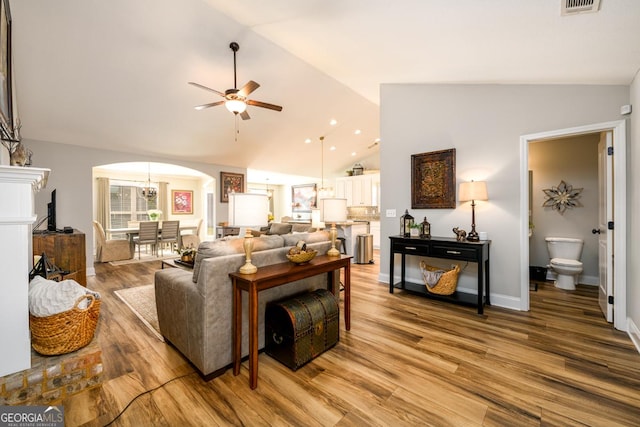 living room featuring hardwood / wood-style flooring, ceiling fan, and vaulted ceiling