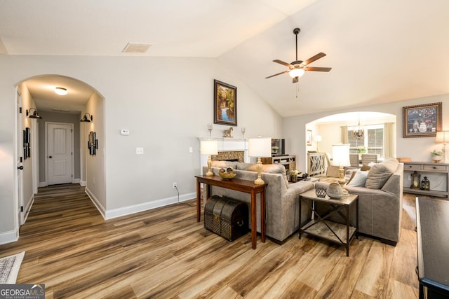 living room with ceiling fan with notable chandelier, hardwood / wood-style floors, and lofted ceiling