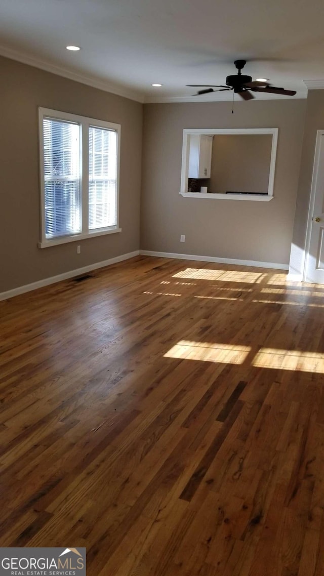 empty room with ornamental molding, ceiling fan, and dark wood-type flooring