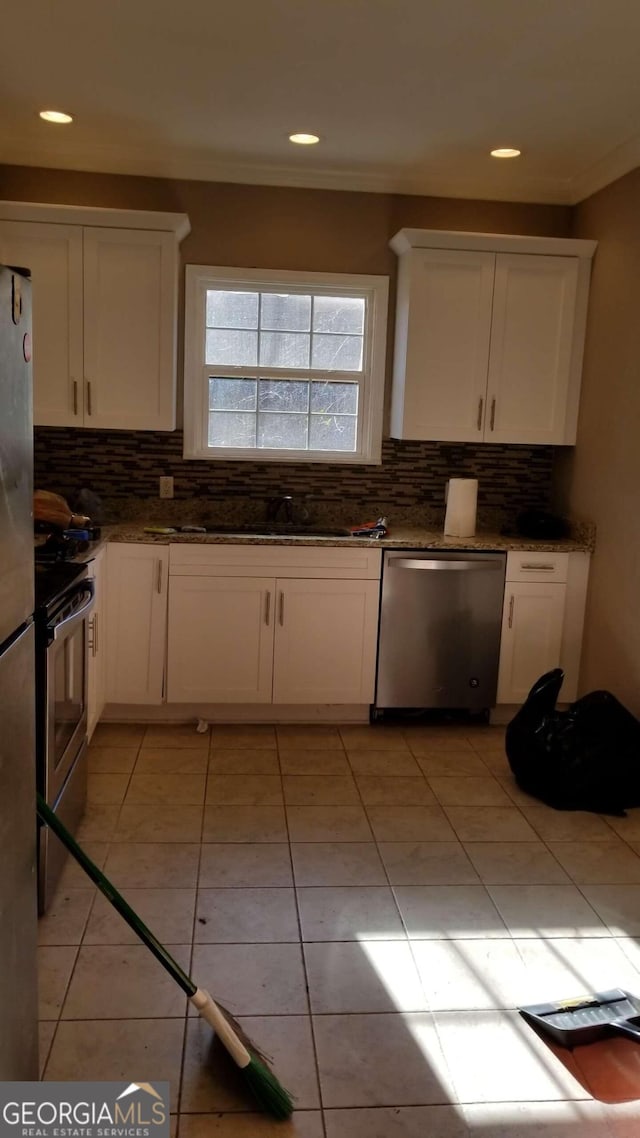 kitchen featuring backsplash, sink, light tile patterned floors, appliances with stainless steel finishes, and white cabinetry