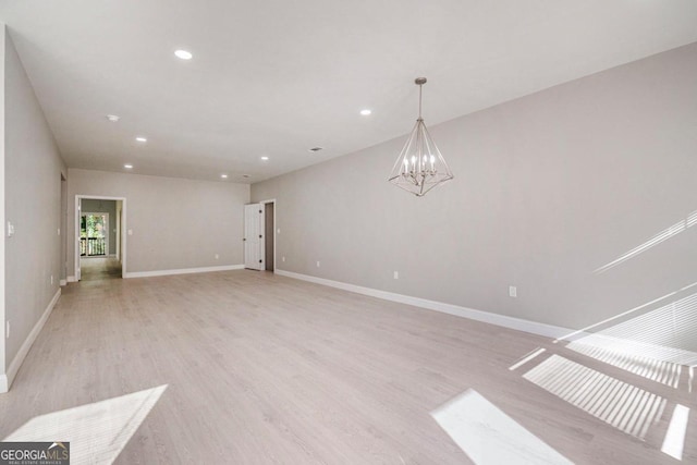 spare room featuring light hardwood / wood-style floors and an inviting chandelier