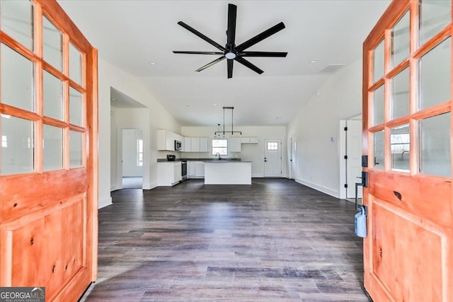 unfurnished living room with dark hardwood / wood-style flooring, vaulted ceiling, ceiling fan, and sink