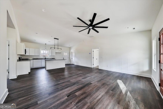 unfurnished living room with ceiling fan, dark wood-type flooring, and vaulted ceiling