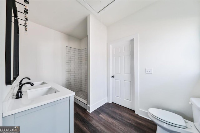 bathroom with vanity, toilet, wood-type flooring, and tiled shower