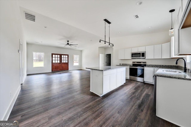 kitchen featuring white cabinetry, sink, stainless steel appliances, pendant lighting, and a kitchen island