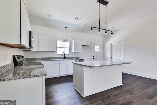 kitchen featuring a center island, white cabinetry, hanging light fixtures, and stainless steel appliances