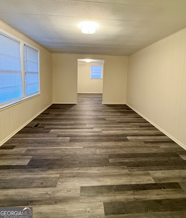 unfurnished room with dark hardwood / wood-style flooring and a textured ceiling