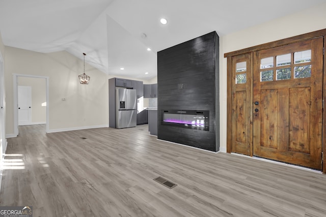 unfurnished living room featuring a fireplace, light wood-type flooring, and vaulted ceiling