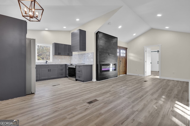 kitchen with gray cabinetry, lofted ceiling, light wood-type flooring, and appliances with stainless steel finishes