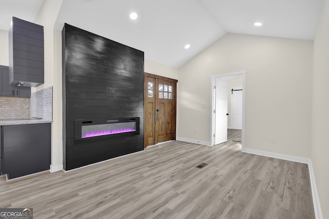 unfurnished living room with a fireplace, light hardwood / wood-style floors, and lofted ceiling