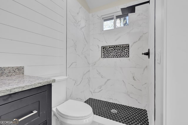 bathroom featuring tiled shower, vanity, and toilet