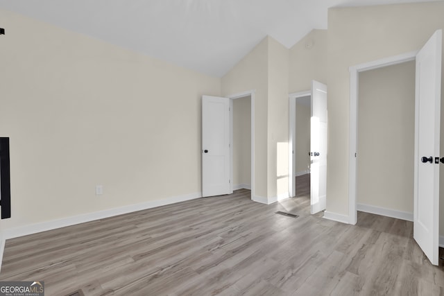 unfurnished bedroom with light wood-type flooring, high vaulted ceiling, and a closet