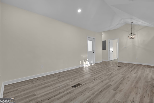 unfurnished living room featuring light hardwood / wood-style floors, lofted ceiling, electric panel, and a chandelier