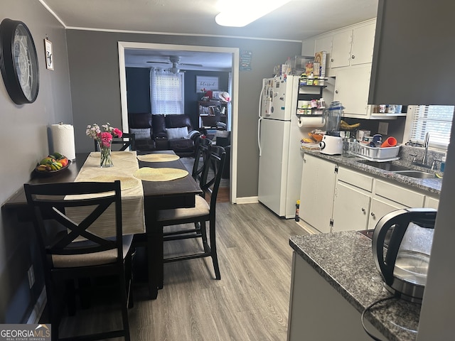 kitchen with ceiling fan, sink, light hardwood / wood-style flooring, crown molding, and dark stone counters