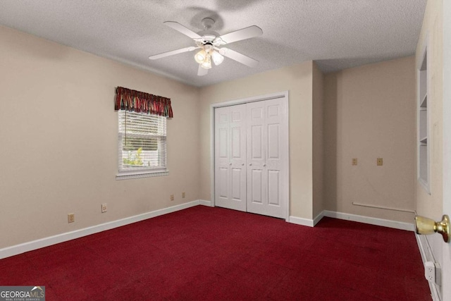 unfurnished bedroom with ceiling fan, a closet, dark carpet, and a textured ceiling