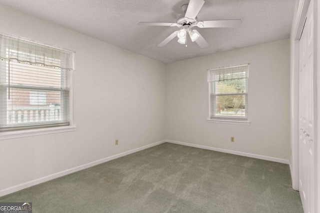 carpeted spare room with ceiling fan, a healthy amount of sunlight, and a textured ceiling