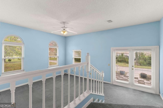 hall with carpet, a textured ceiling, and a wealth of natural light