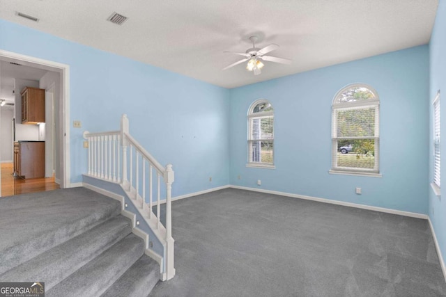 carpeted spare room featuring ceiling fan and a textured ceiling