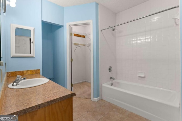 bathroom featuring vanity, a textured ceiling, tiled shower / bath combo, and tile patterned flooring