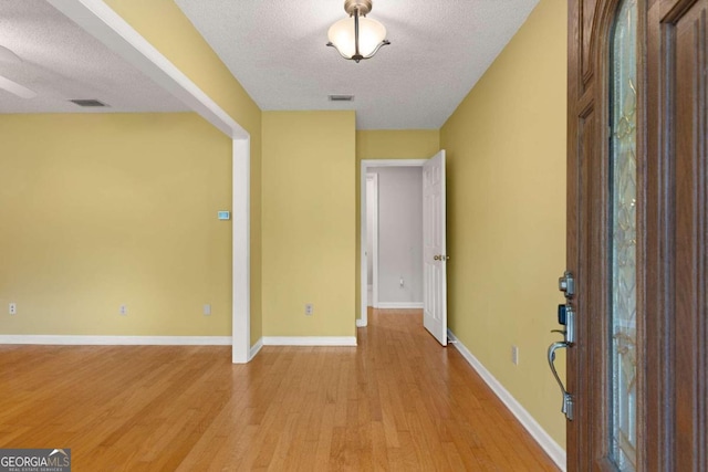 foyer entrance featuring a textured ceiling and light hardwood / wood-style flooring