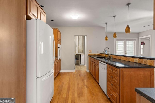 kitchen featuring sink, wine cooler, pendant lighting, white appliances, and light wood-type flooring