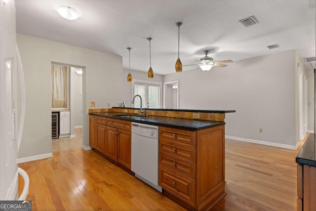 kitchen featuring white appliances, sink, light wood-type flooring, decorative light fixtures, and beverage cooler