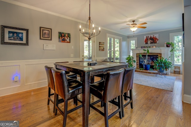 dining space with ceiling fan with notable chandelier, light hardwood / wood-style flooring, and crown molding