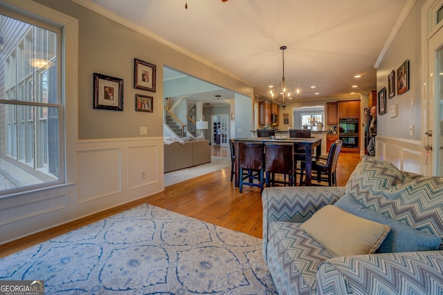 dining area with light hardwood / wood-style floors, ornamental molding, and a notable chandelier