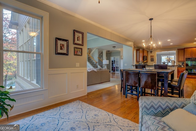 dining room featuring light wood-type flooring, ornamental molding, and a chandelier