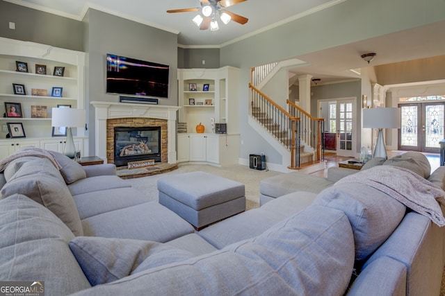 living room featuring ceiling fan, french doors, built in features, a fireplace, and ornamental molding