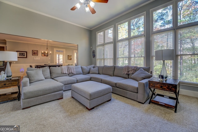 living room featuring carpet, ceiling fan with notable chandelier, a healthy amount of sunlight, and ornamental molding