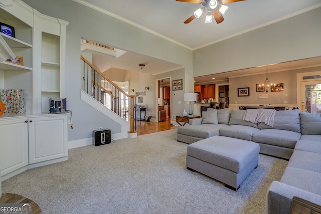 carpeted living room featuring ceiling fan with notable chandelier and ornamental molding