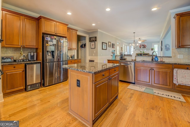 kitchen featuring ceiling fan, sink, light hardwood / wood-style flooring, a kitchen island, and appliances with stainless steel finishes