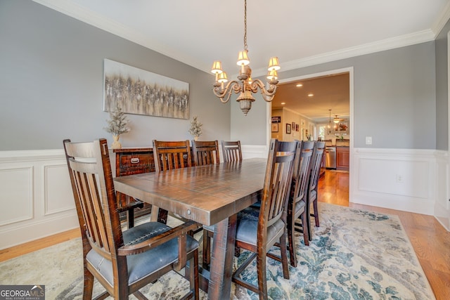 dining space featuring ornamental molding, light hardwood / wood-style flooring, and a chandelier