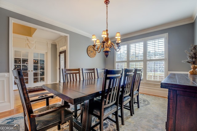 dining room with a chandelier, plenty of natural light, ornamental molding, and light wood-type flooring