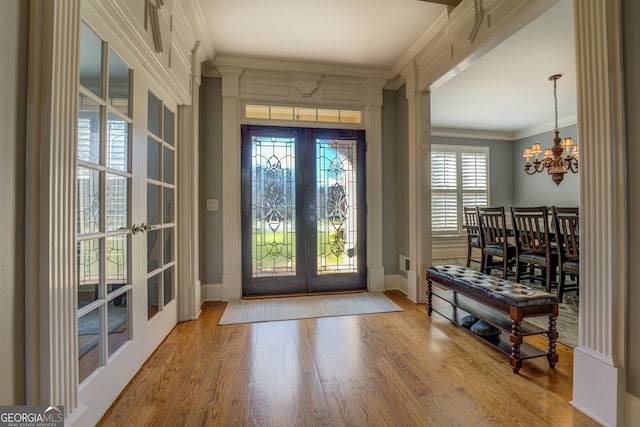 foyer entrance featuring a chandelier, french doors, light wood-type flooring, and crown molding