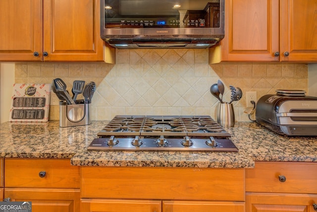 kitchen with stone counters, appliances with stainless steel finishes, and decorative backsplash