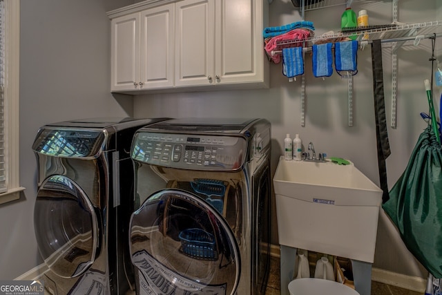 laundry room with cabinets, dark tile patterned flooring, washer and clothes dryer, and sink